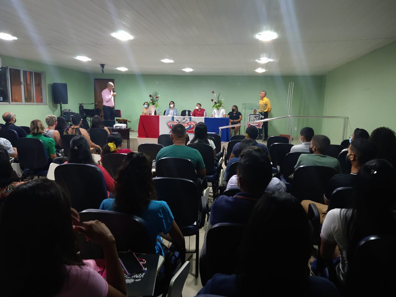 Coordenador Djair falando para plateia e mesa