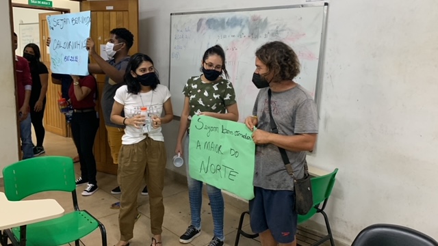 Docentes e discentes com cartazes dialogando